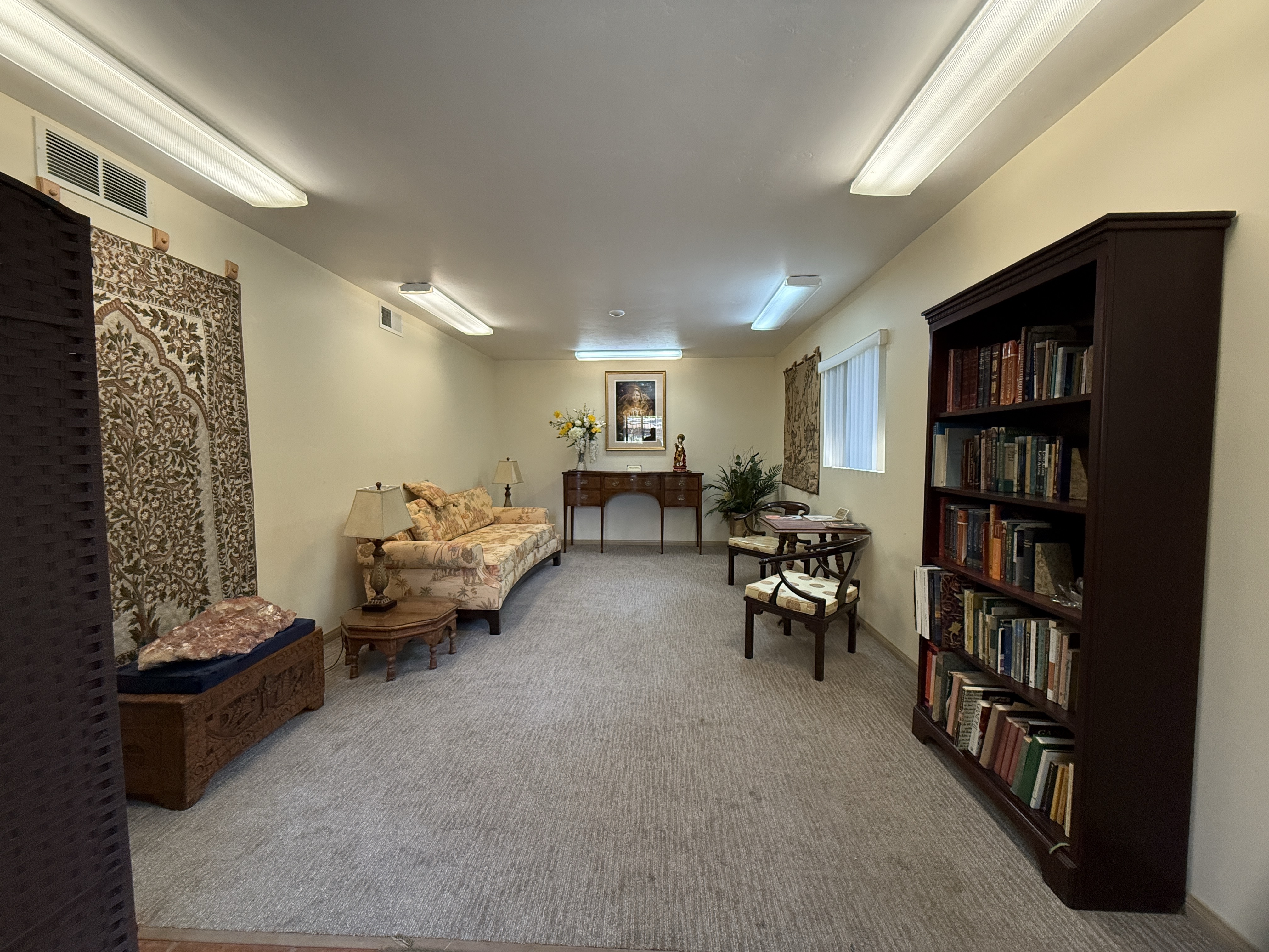 The guest library reading room, with bookcases, a sofa, and a wall tapestry
